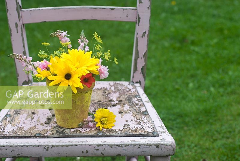 Cut garden flower arrangement - yellow marigolds, crimson flax, fennel and toadflax in yellow flower pot