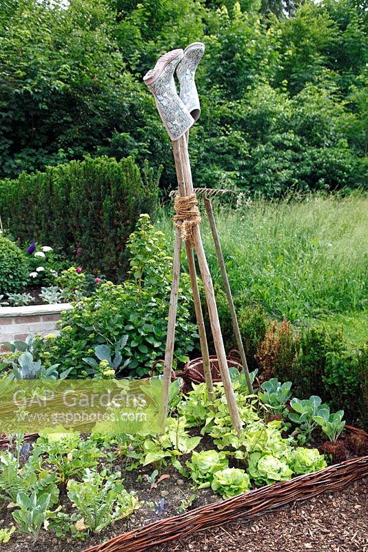 Raised bed of hazel rods with vegetables and wellies on top of bean supports, June, Sigmaringen, Germany