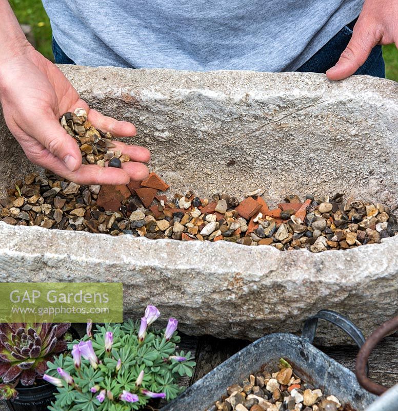 Practical step-by-step guide to planting a stone alpine trough with rock plants. All rock plants need good drainage, so cover the drainage holes first with crocks - to prevent them becoming blocked and then cover with gravel to a depth of 2-3cm.