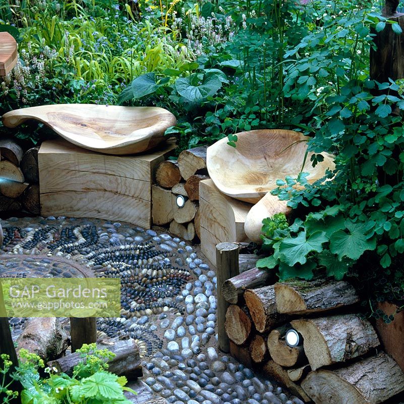 Pebble mosaic path and sunken floor, edged in sawn timbers supporting curving wooden seats.