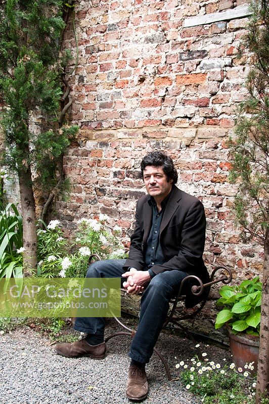 Rupert Wheeler, owner, designer and architect, sitting in his garden.
