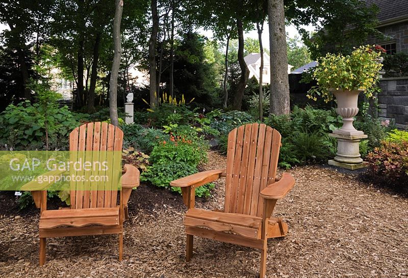 Wooden adirondack chairs in backyard garden in summer, Jardin Secret garden, Quebec, Canada