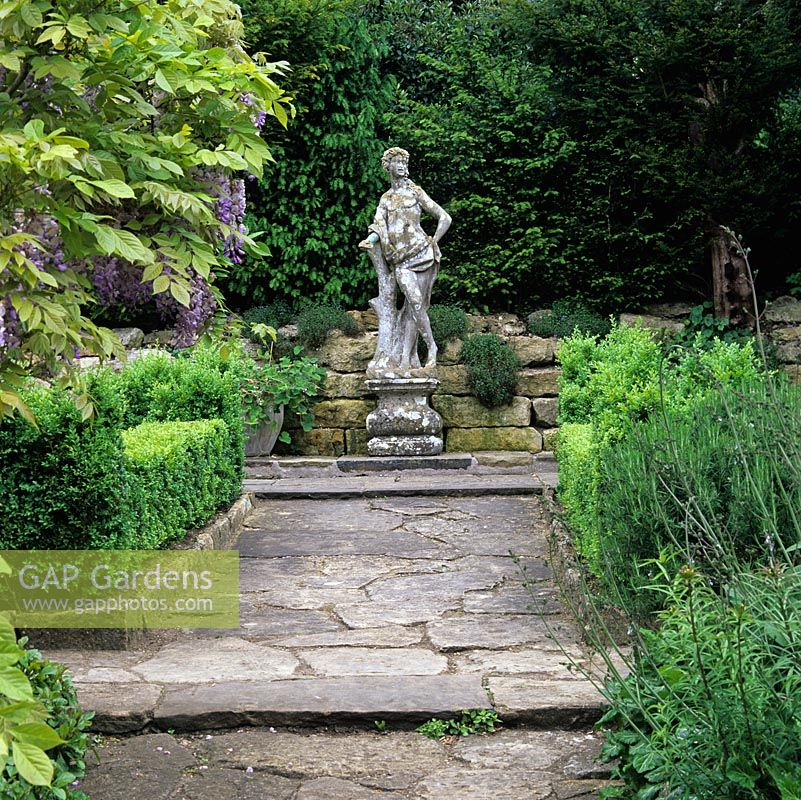 Italian stone statue of a young nobleman creates a focal point on the yew-fringed borders of the formal Casita garden.
