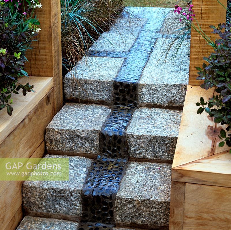 Granite steps have in the centre an innovative panel of pebbles set in concrete and sealed with resin.