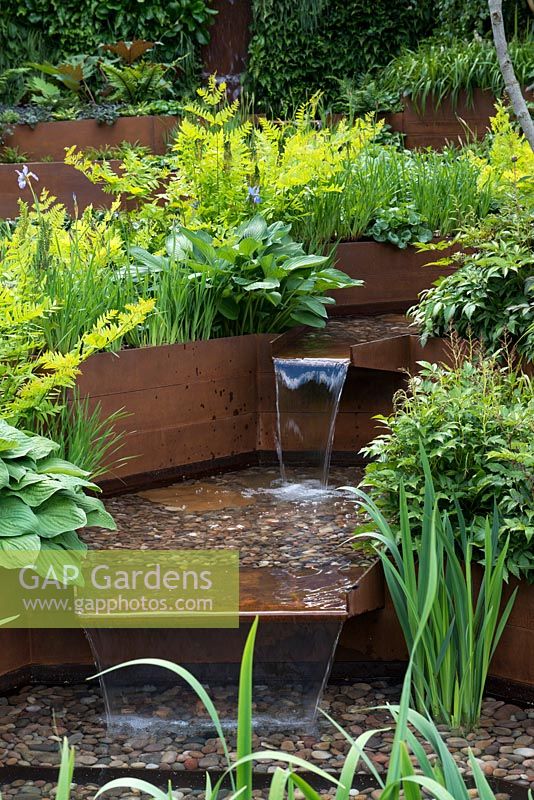 A contemporary garden with rusted corten steel terraces forming a cascading water feature.