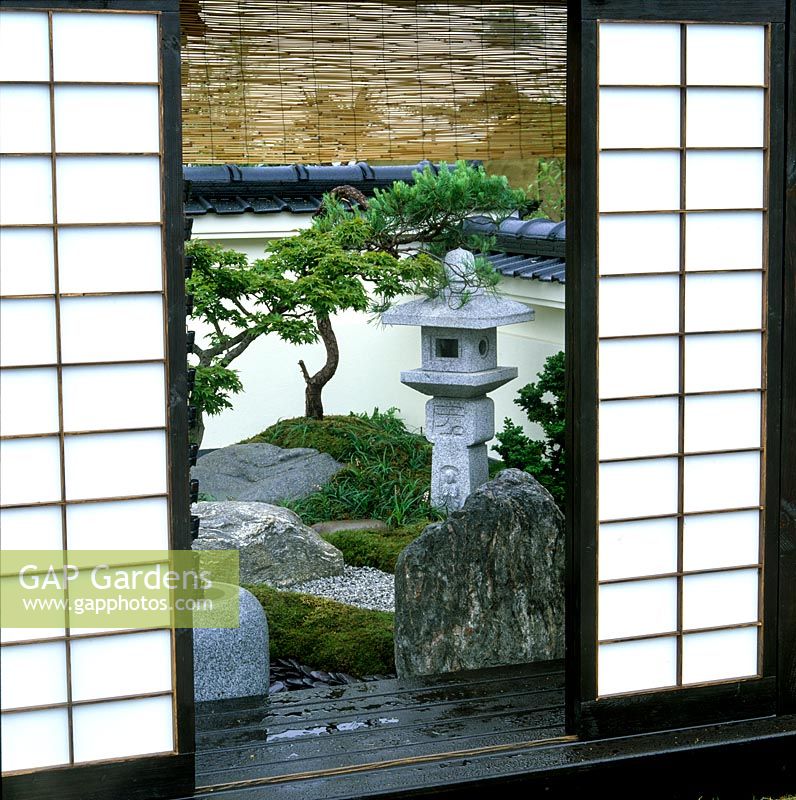 Doors slide back on verandah to reveal tiny courtyard garden in the restrained tsubo niwa style. Maple, rocks, moss and stone create serene ambience.