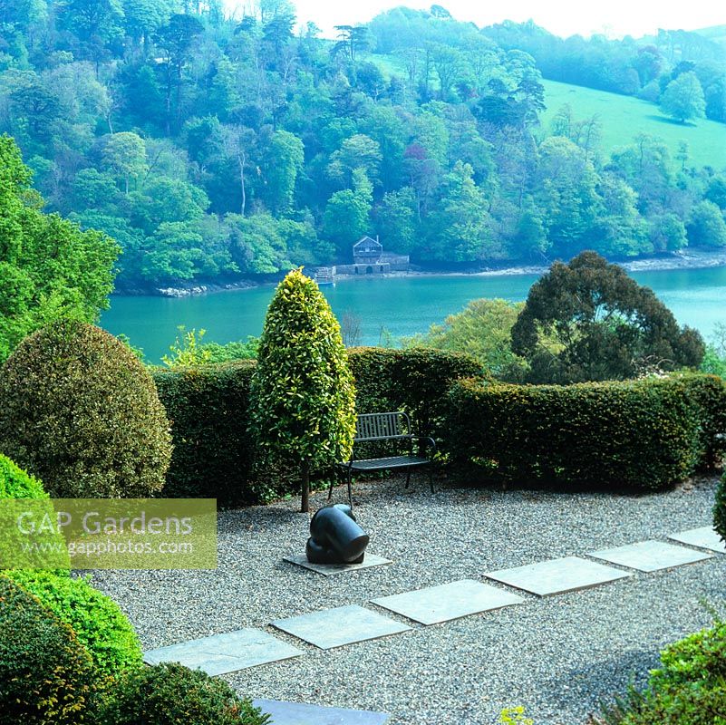 Japanese style terrace enclosed by yew hedges. Sculptor Bridget McCrums bronze statue by box and bay topiary.