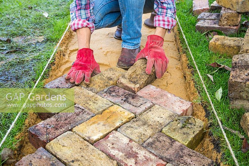 Arrange the bricks to form transverse chevrons in the desired direction of travel. Building a brick path