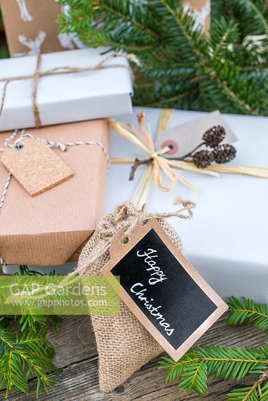 Christmas present wrapped in Hessian, accompanied with Yew foliage. Featuring cork tag and Alder decoration