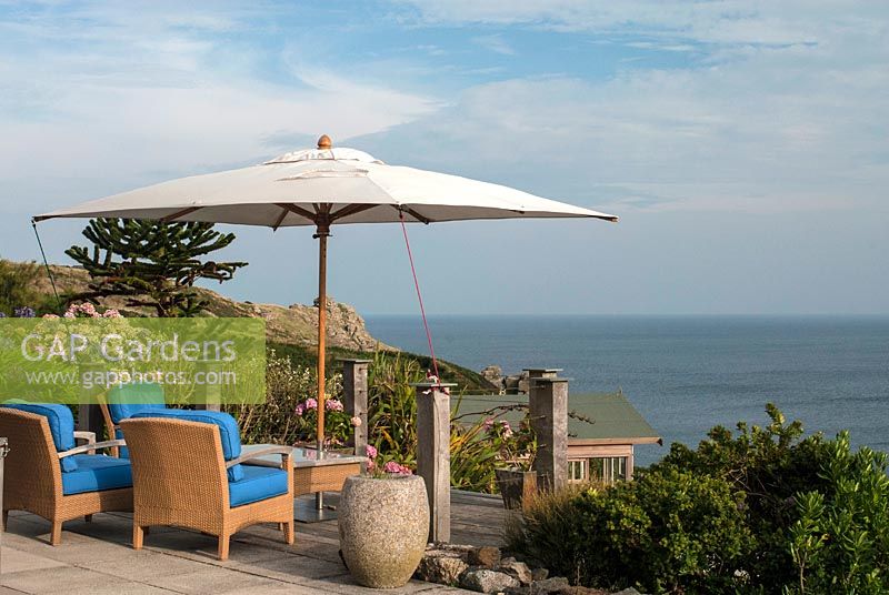 Coastal garden with Hydrangeas, chairs, a parasol and the sea. The Lizard, Cornwall in August