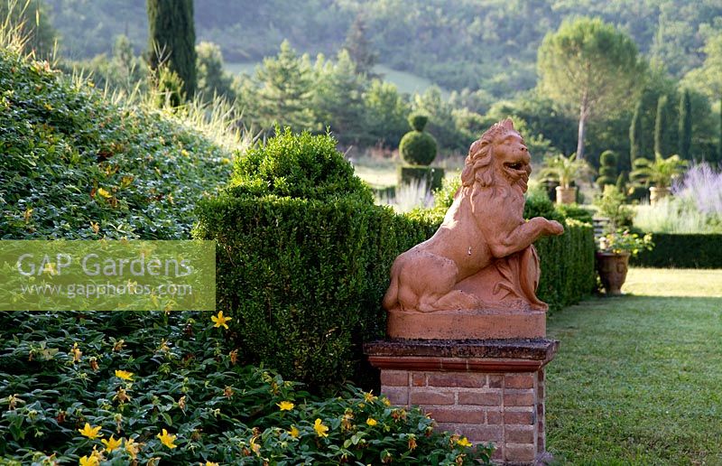 A terracotta lion at Domaine de Chatelus de Vialar.  With topiary of yew, a low clipped box hedge and bank of Hypericum calycinum