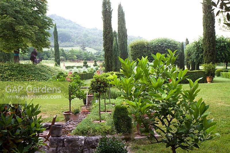 Long view of the garden at Domaine de Chatelus de Vialar.  Formal elements are in front of the house.  Looking towards group of topiary yew.   