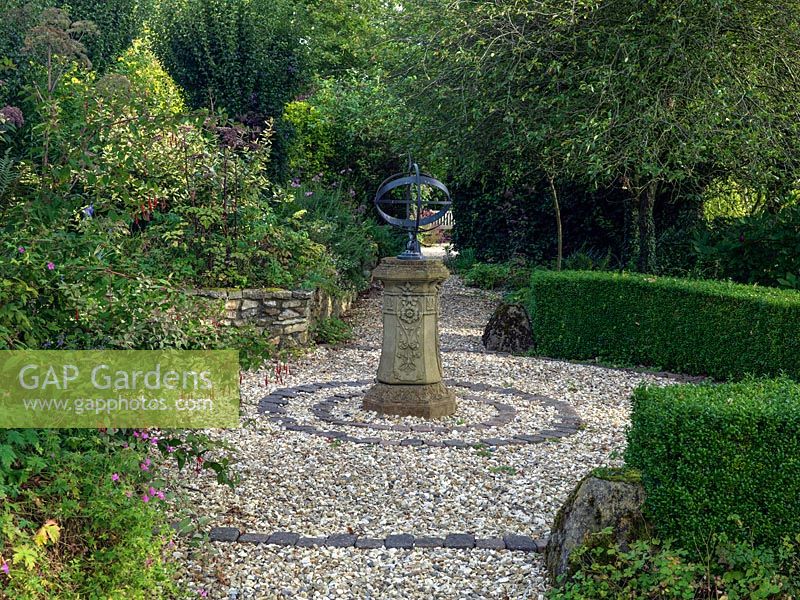 An ornamental sundial in the centre of a round gravel bed in the Terraced Garden.