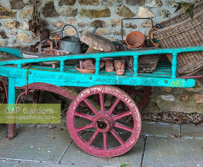 A colourful painted hand cart filled with gardening paraphernalia.
