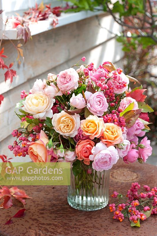 Bunch of flowers with Rosa and branches of Euonymus with berries