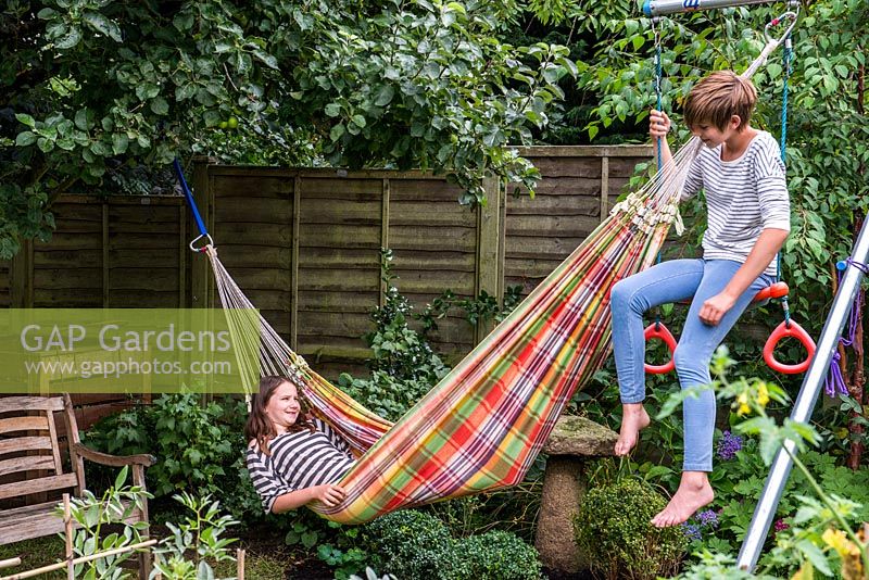 Lily, 10, lazes in a hammock whilst Scarlett, 13, perches on the swing frame.