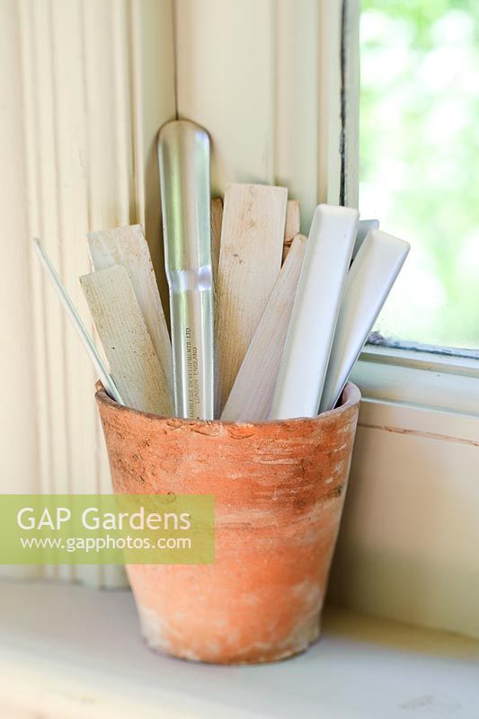 Plant labels and dibber in old flower pot on window sill