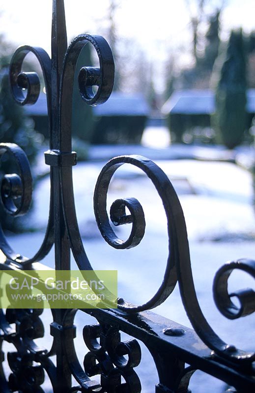 Wrought iron gate detail with snow covered garden. Clare College Fellows' Garden. Cambridge