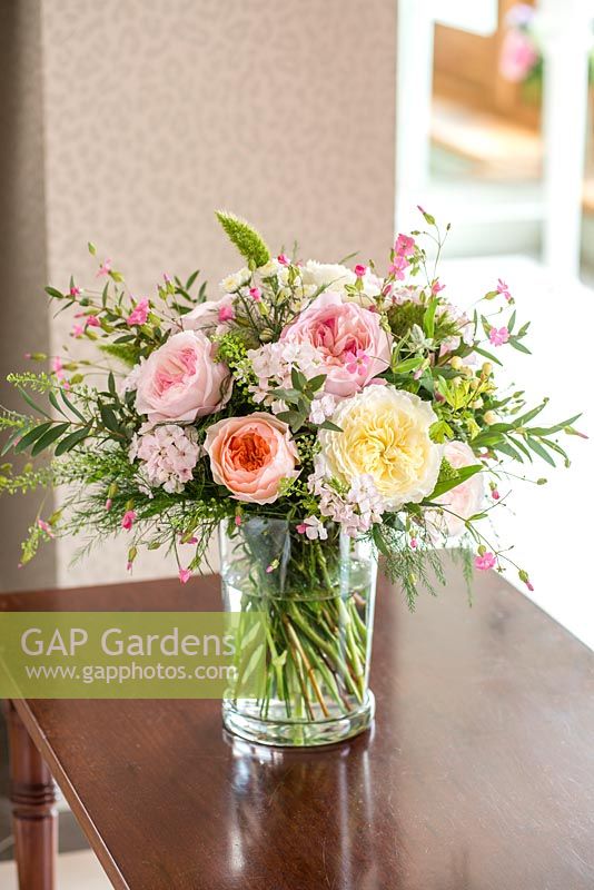 A cut flower arrangement with roses on a side table indoors
