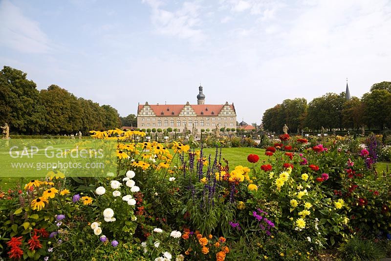 Mixed flower borders with red, white and yellow Dahlia, Rudbeckias at the Weikersheim Palace garden in late summer, Wurttemberg, Germany
