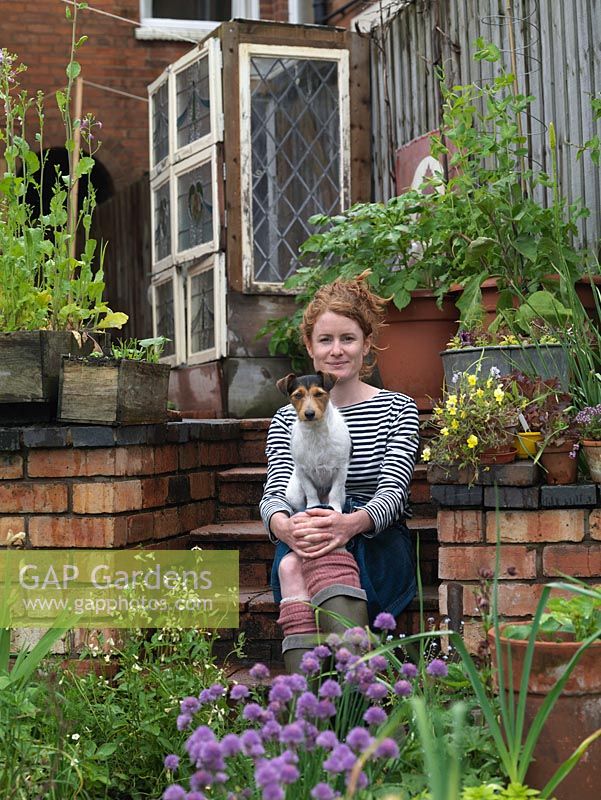 Alys Fowler, gardener, author and TV presenter, sits on the steps in her 18m x 6m back garden. On her lap, Isabelle, a Jack Russell dog.