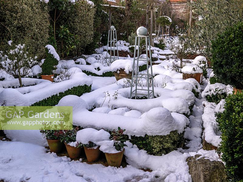 Snow covered small walled formal garden 