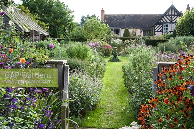 View into Sundial Garden framed with heleniums, monardas and salvias, with asters full of buds beyond. Wollerton Old Hall, nr Market Drayton, Shropshire, UK