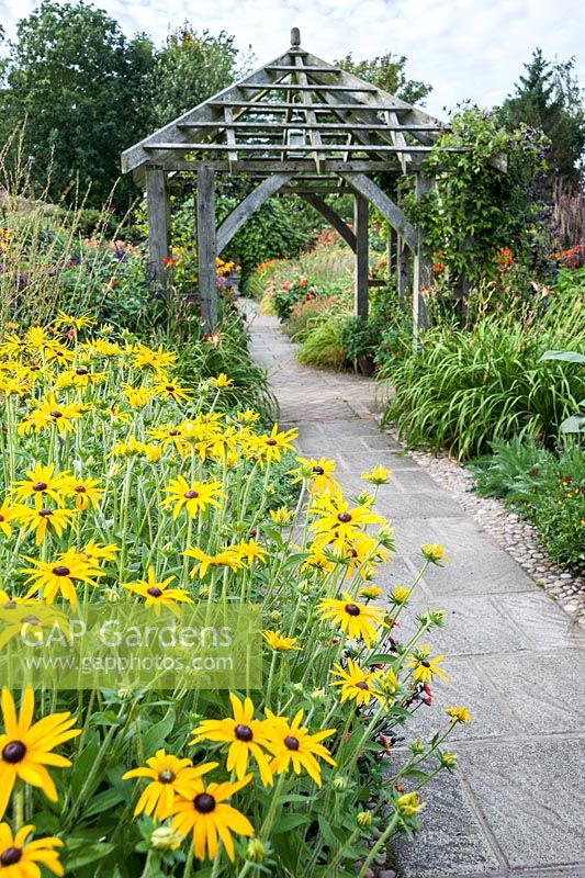 Path through the Lanhydrock Garden, otherwise known as the hot garden, passes below a wooden pergola surrounded by rudbeckias and other choice perennials. Wollerton Old Hall, nr Market Drayton, Shropshire, UK