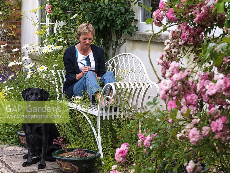 Julia Whiteaway, accompanied by her black labrador, sits in the courtyard overlooking her one-acre country garden.