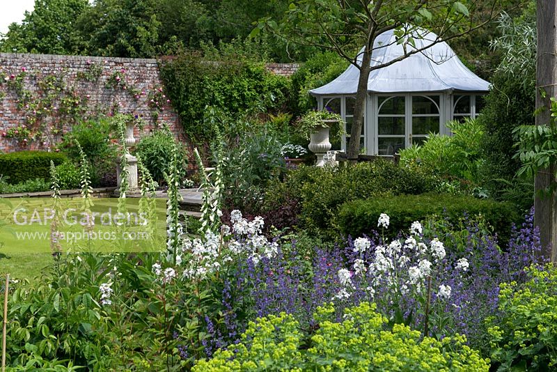 A walled garden with domed summer house and mixed border planted with foxglove, sweet rocket, catmint and alchemilla.