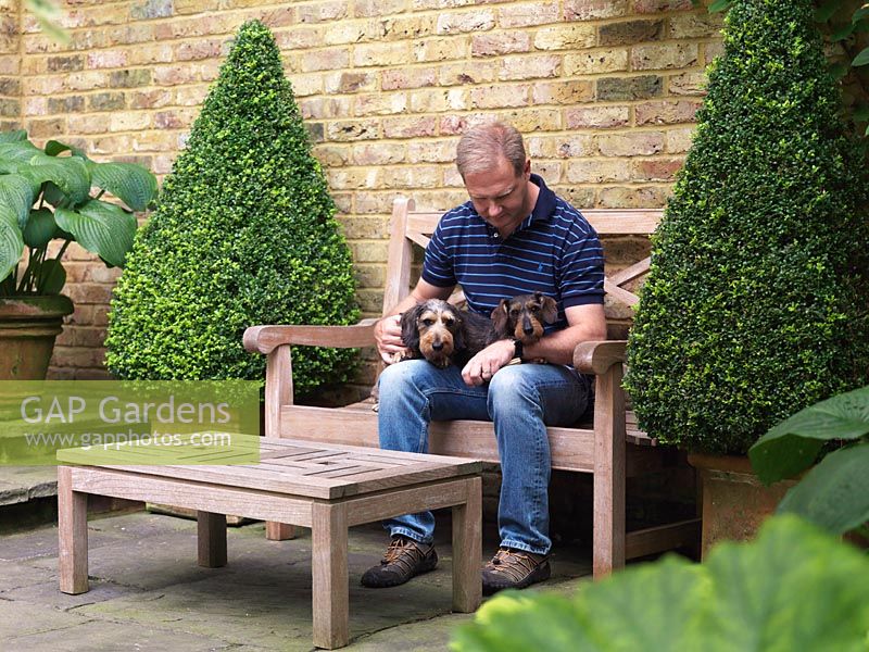 Paul Morrow sits on the terrace with his two young miniature wire-haired dachshunds.