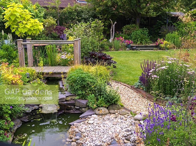 16m square back garden with gravel and boggy areas, wildlife pond, bridge and stream.