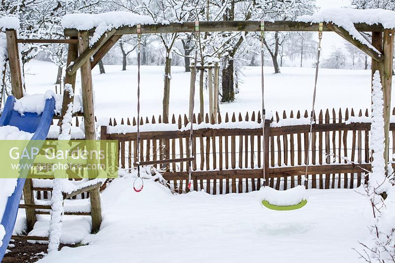 Winter in the children's corner with swing seat and slide