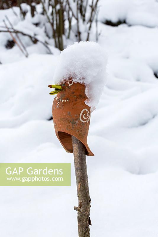 Ceramic bird on wooden stake with snow cap
