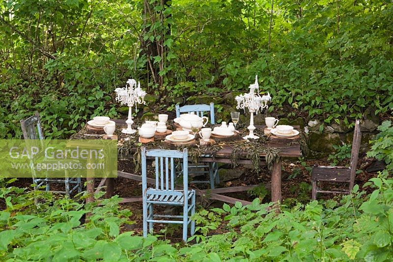 Wooden dining table and chairs set up in the Shade Garden in the La Seigneurie de L'Ile d'Orleans private estate garden in summer, Saint-Francois, Ile d'Orleans, Quebec, Canada