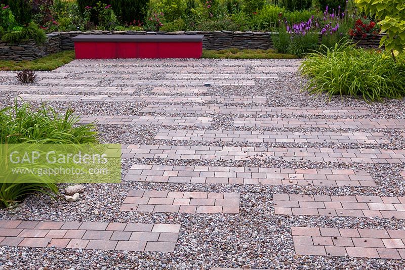 Gravel and brick surface. Dark red bench gives a contrast in general monochromatic set of plant colors
