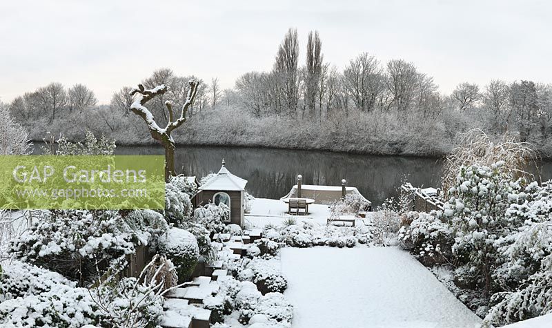 River Thames garden designed by Andy Sturgeon. Box topiary, grasses and architectural plants covered in snow.
