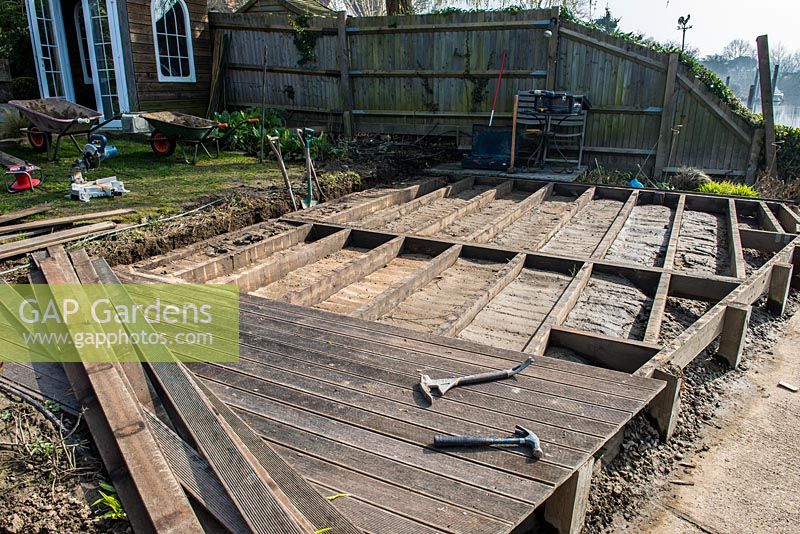 After weeks of flooding, a riverside deck has to be completely rebuilt. The first step is to remove the hardwood decking planks, revealing the softwood subframe which is rotting in parts because a build-up of wet mud has been deposited between the joists.