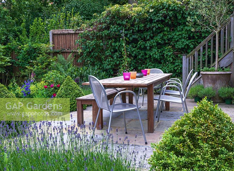 A raised patio, with dining table, creates an outdoor living space in a modern town garden.