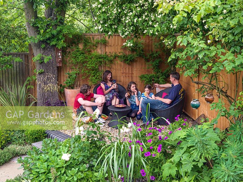 The Monaghan family relax in a shady seating area at the bottom of their modern town garden, Muswell Hill, London.