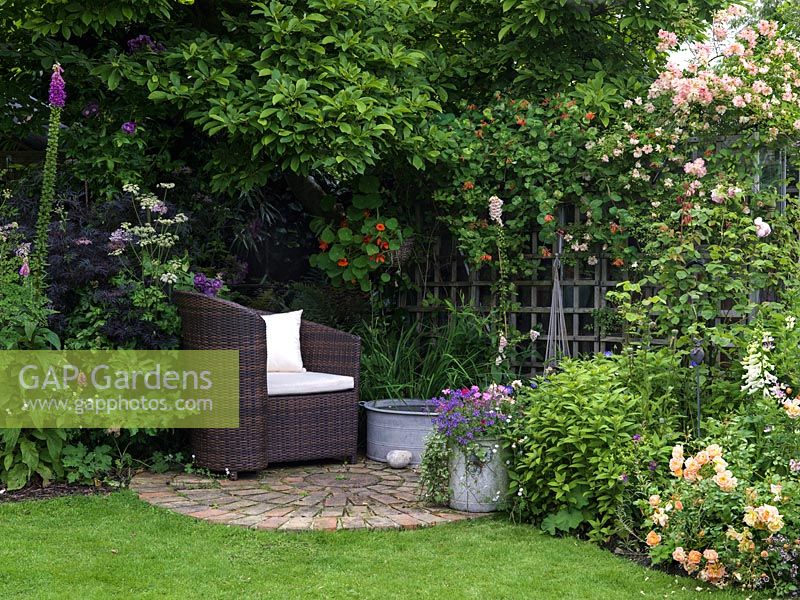 A secluded seating area under a Magnolia tree and by a small container pond.