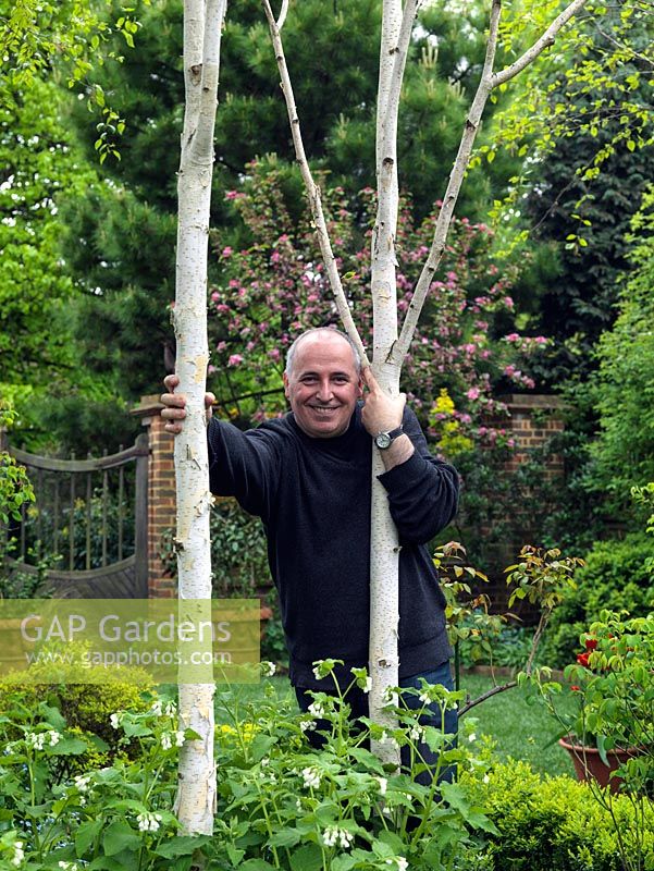 Paul Minter between two silver birches planted in the woodland area of his 50m x 9m long, town garden.