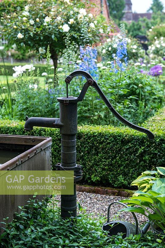 A decorative water pump beside a pond in a galvanised trough.