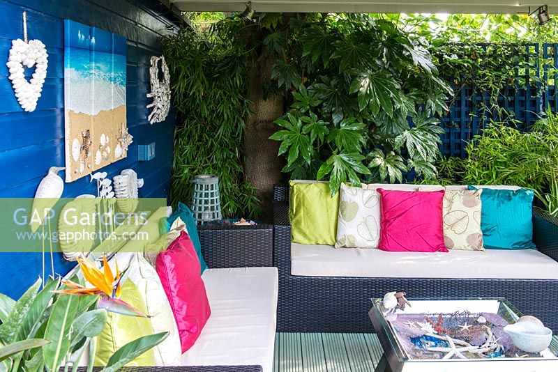 A covered seating area with seaside inspired decorations, sofa and table.
