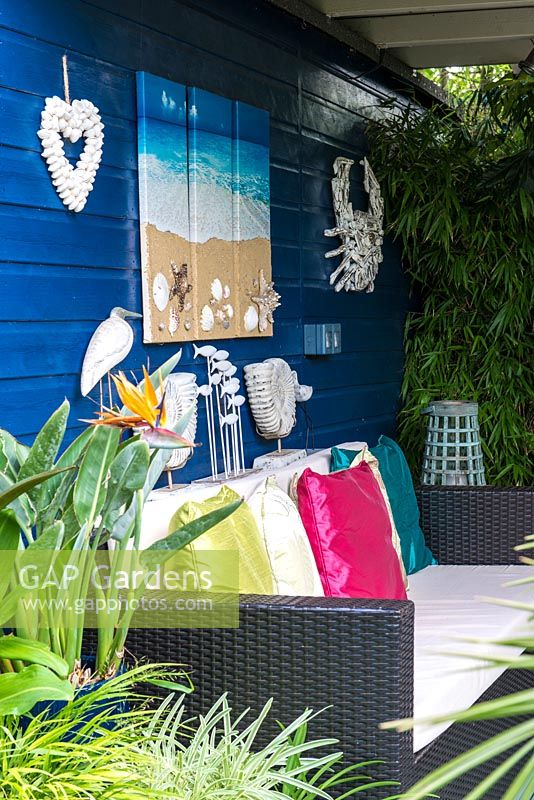 A covered seating area with seaside inspired decorations and sofa.