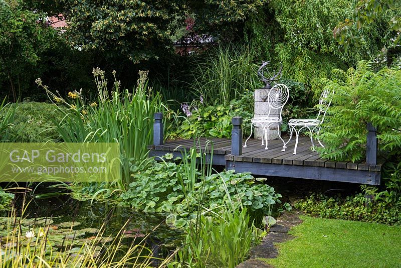 A small raised deck and seating area overlooking a pond.