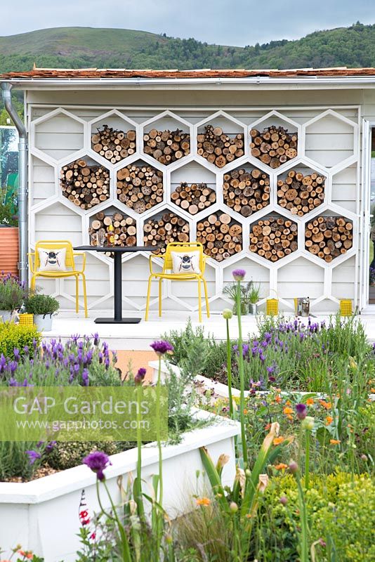 Shed wall covered with hexagonal insect habitats, table and chairs with bee cushions, raised hexagonal beds with Lavandula -  The Bees Knees in support of The Bumblebee Conservation Trust - RHS Malvern Spring Festival 2015