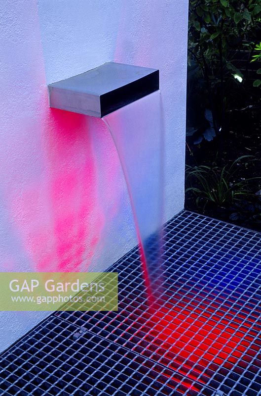 Modern town garden with a water spout and coloured lights, designed by Paul Dracott, London.