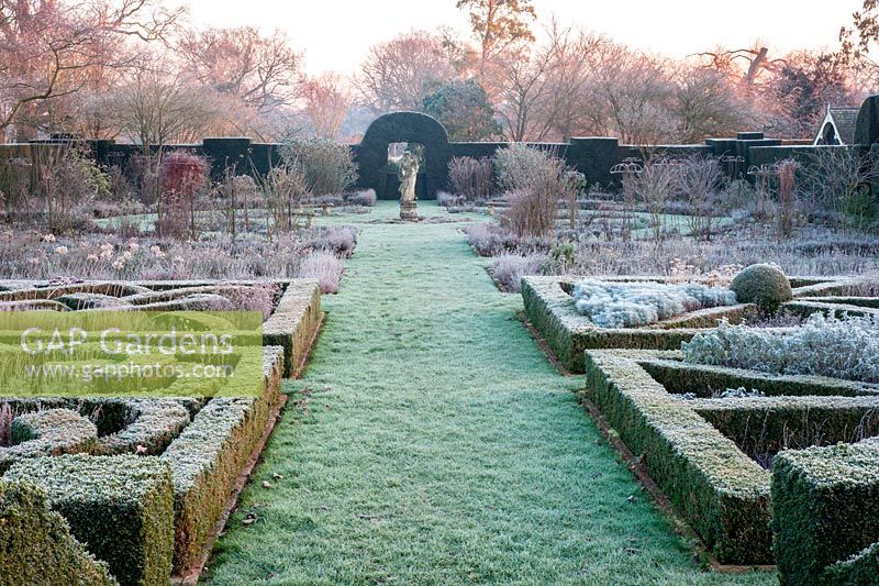 Path leading to statue of Flora in frosted knot garden at Helmingham Hall, Suffolk