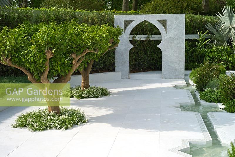 Citrus auranticum - Orange Trees planted in Turkish marble paving and Islamic arch.  The Beauty of Islam by Al Barari garden. RHS Chelsea Flower Show, 2015